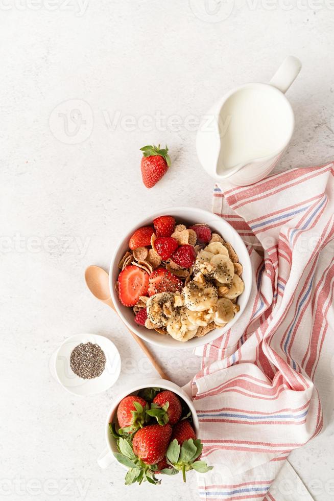 Healthy breakfast, cereal, fresh berries and milk in a bowl, top view photo