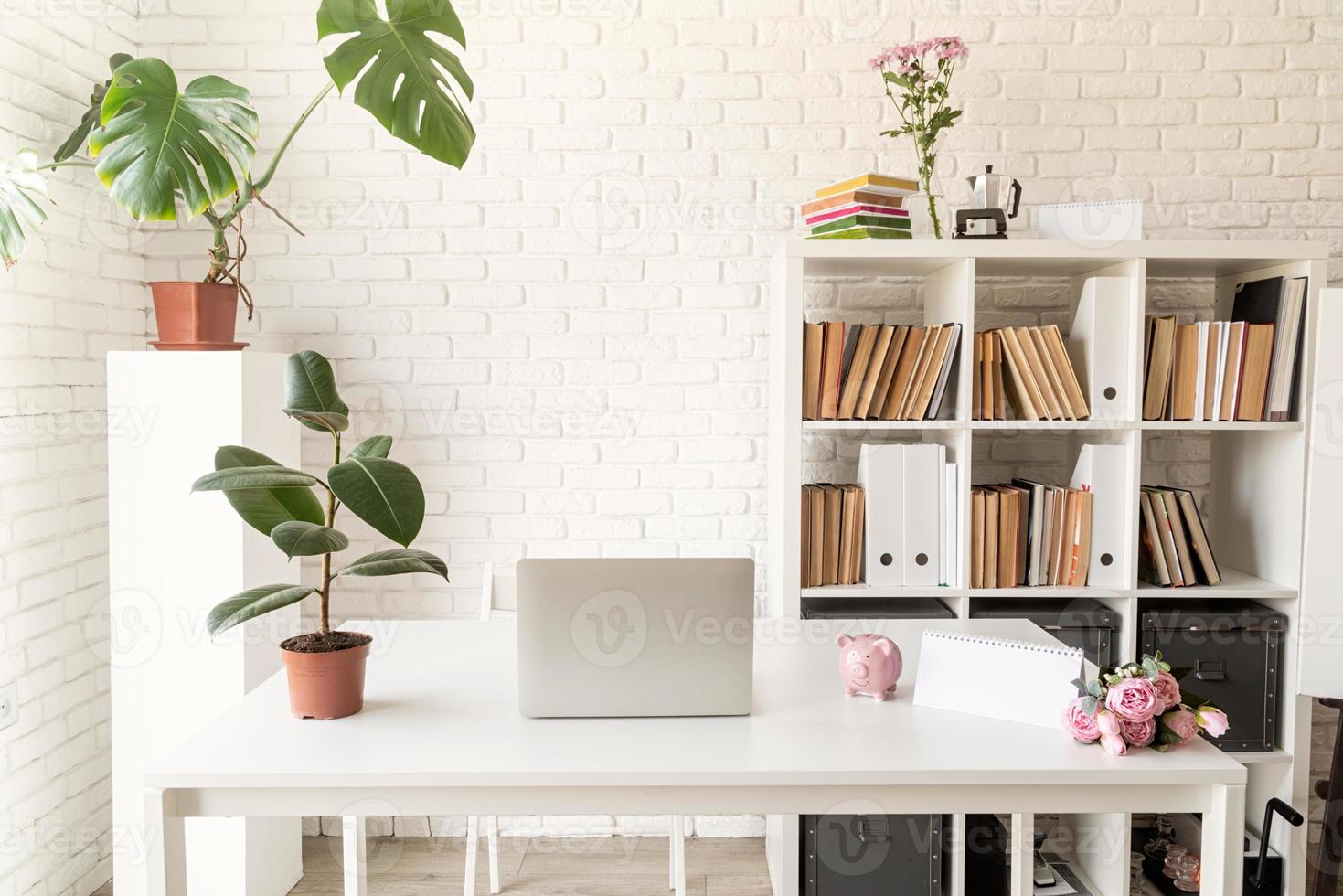 espacio de trabajo acogedor y elegante con computadora portátil, estanterías y plantas foto