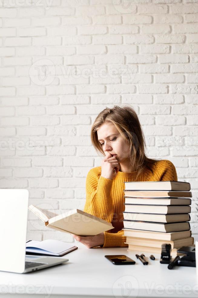 joven pensativa en suéter amarillo estudiando leyendo un libro foto