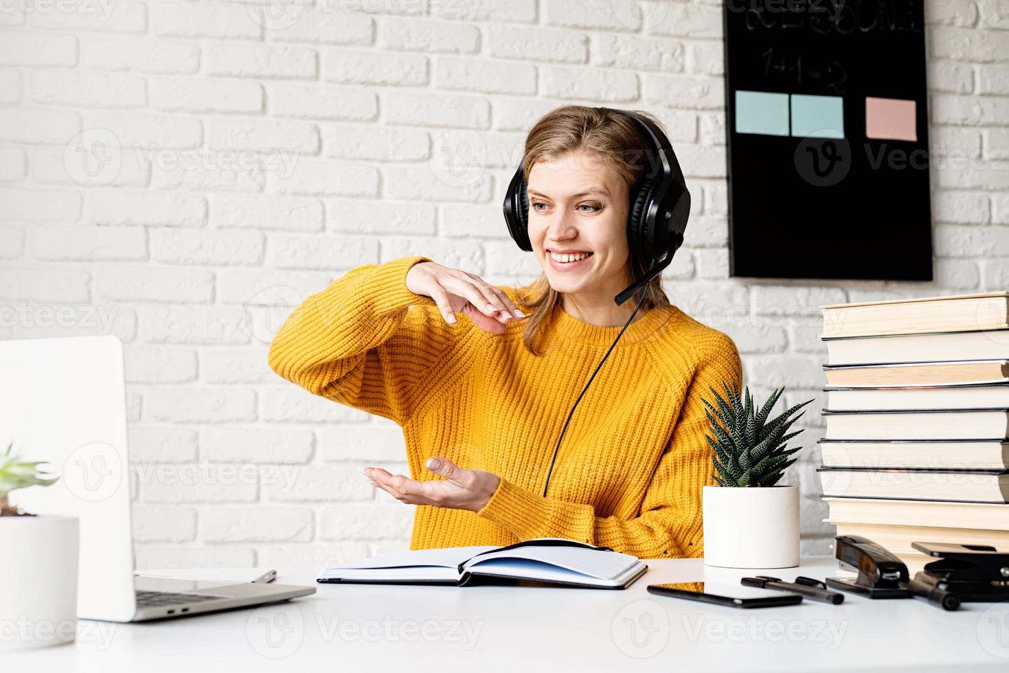 Mujer en auriculares estudiando en línea usando la computadora portátil hablando en video chat foto