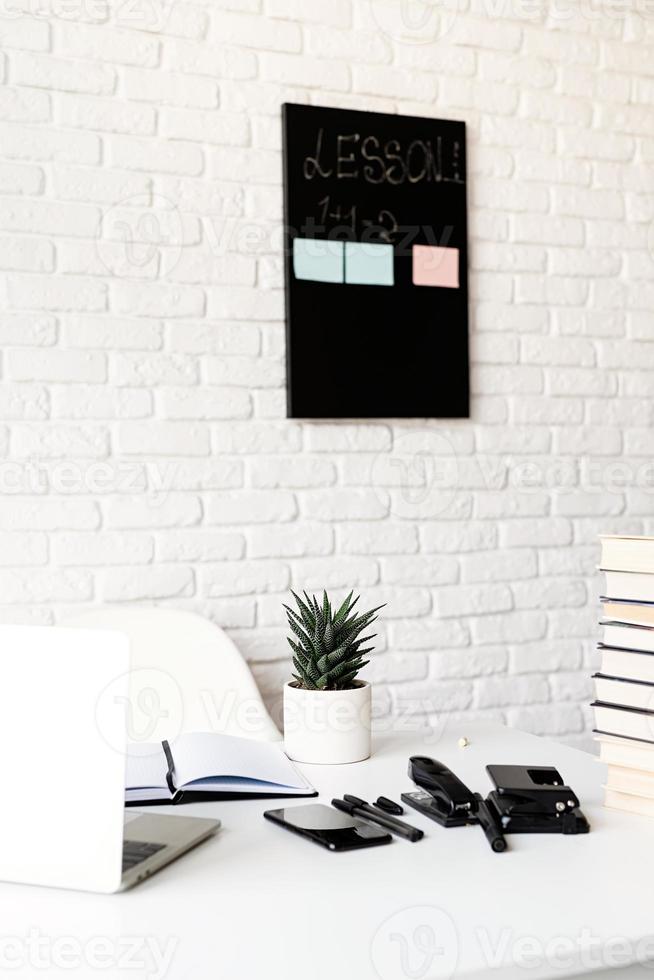 teacher table with laptop, books and stationery photo