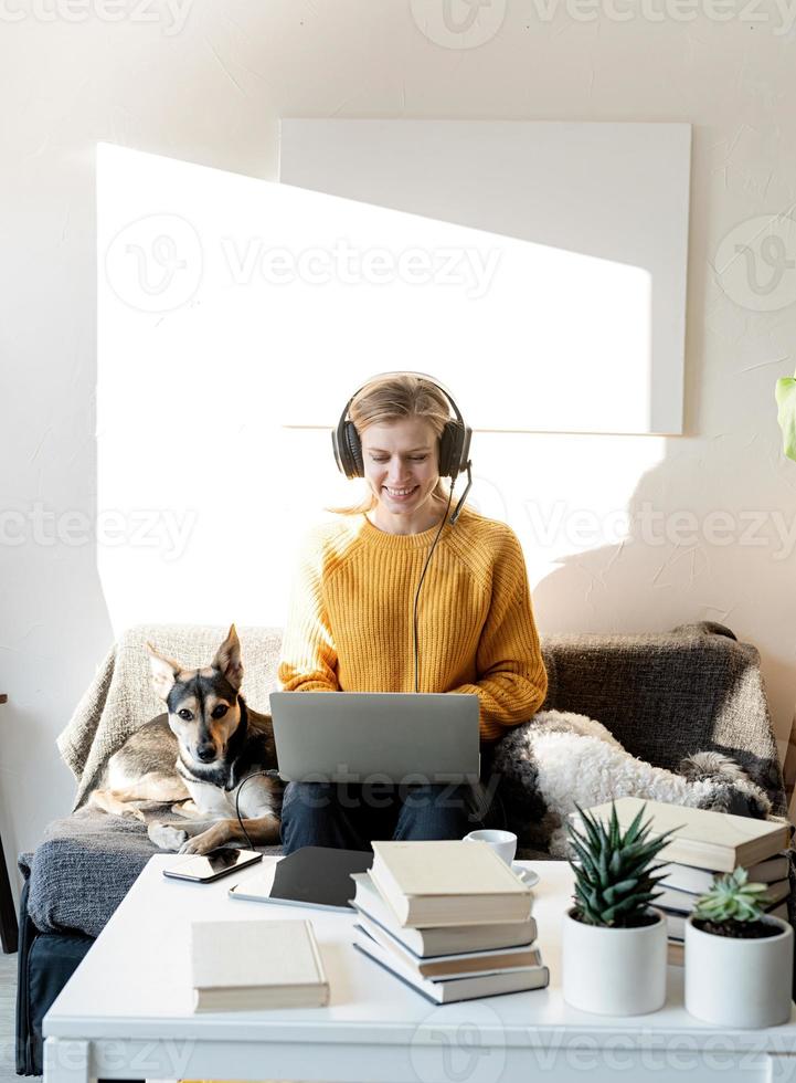 Young smiling woman in black headphones studying online using laptop photo