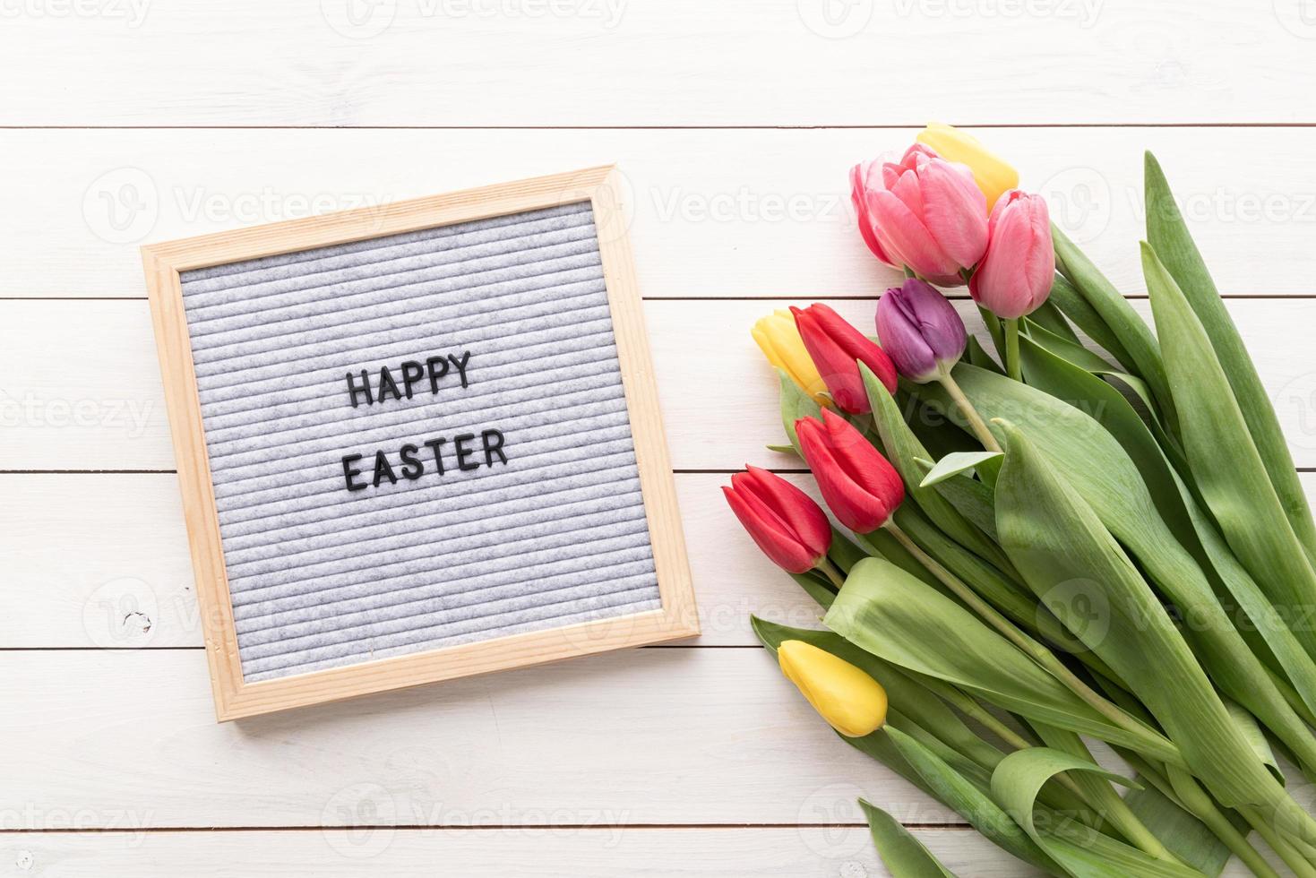 flores de tulipán y tablero de letras con las palabras felices pascuas foto