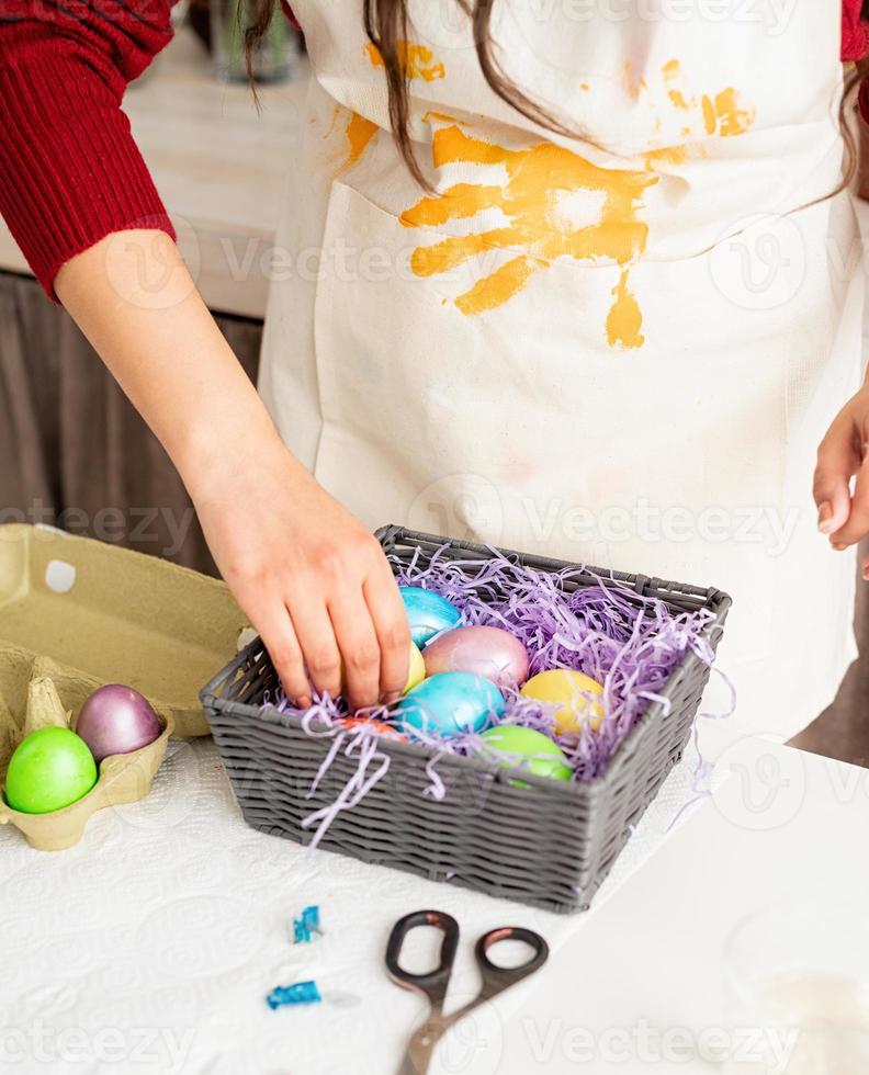 woman in red sweater and white apron decorating colorful easter eggs photo