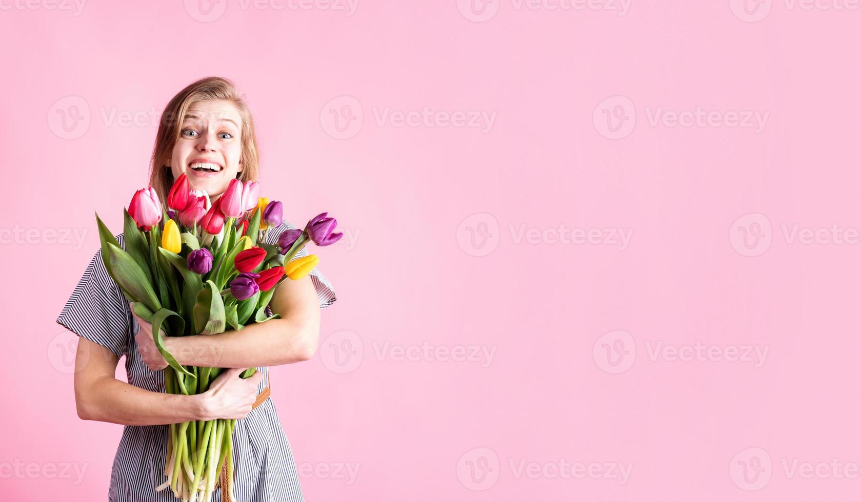 woman holding bouquet of fresh tulips isolated on pink background photo