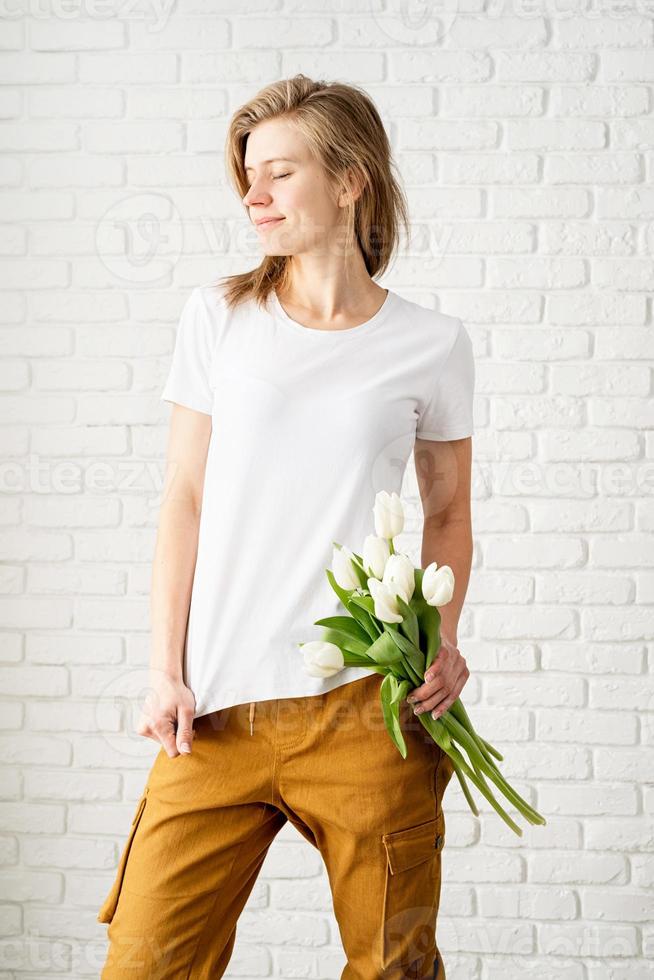 mujer joven, llevando, blanco, camiseta, tenencia, tulipanes, flores foto