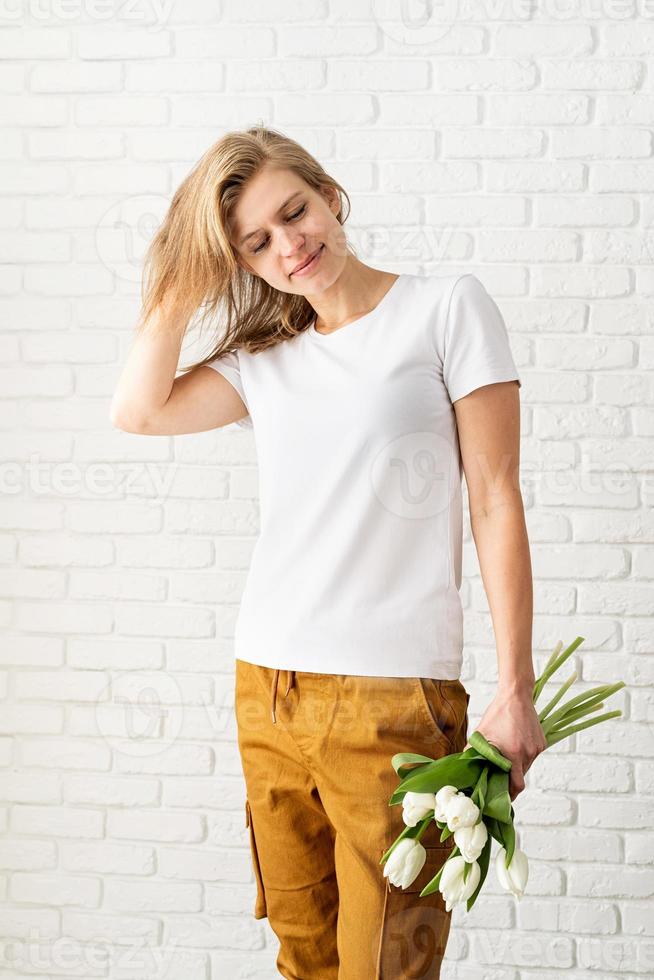 Young woman wearing blank white t-shirt holding tulips flowers photo