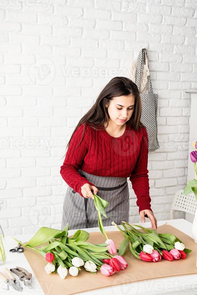 Woman florist making a bouquet of fresh colorful tulips photo