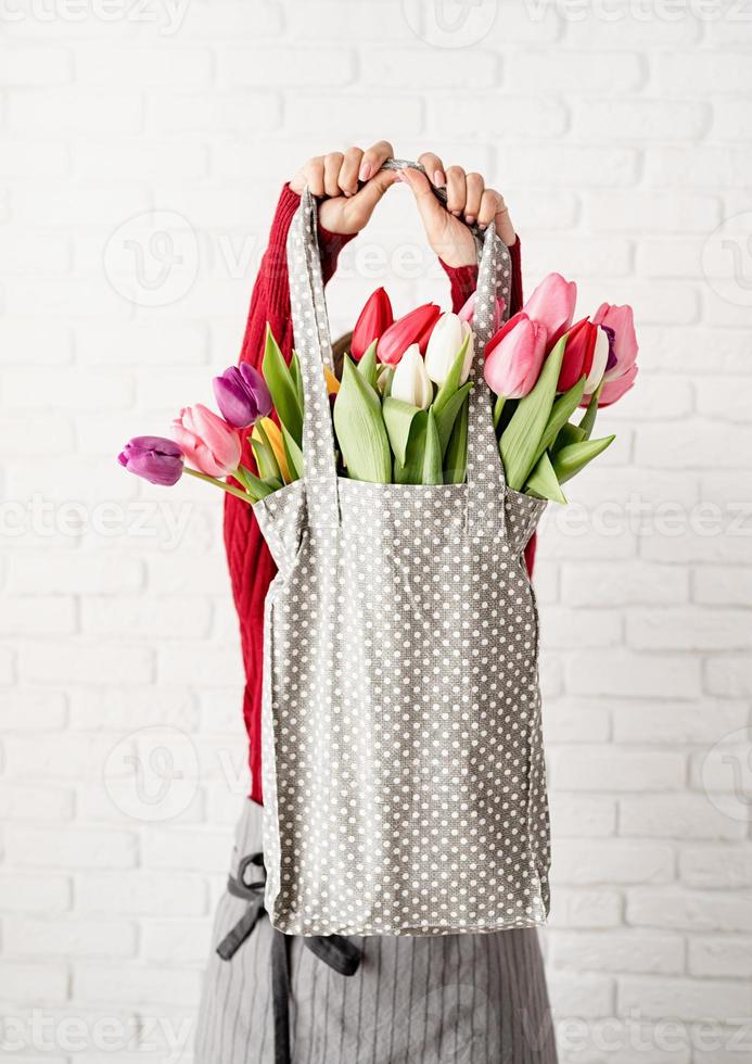 Mujer sosteniendo una bolsa de tela de lunares grises con coloridos tulipanes foto