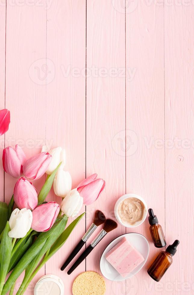 Top view of cosmetics with pink and white tulips photo