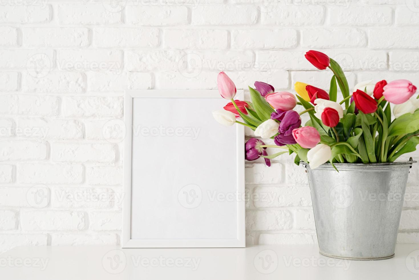 Bucket of fresh tulip flowers and blank frame photo