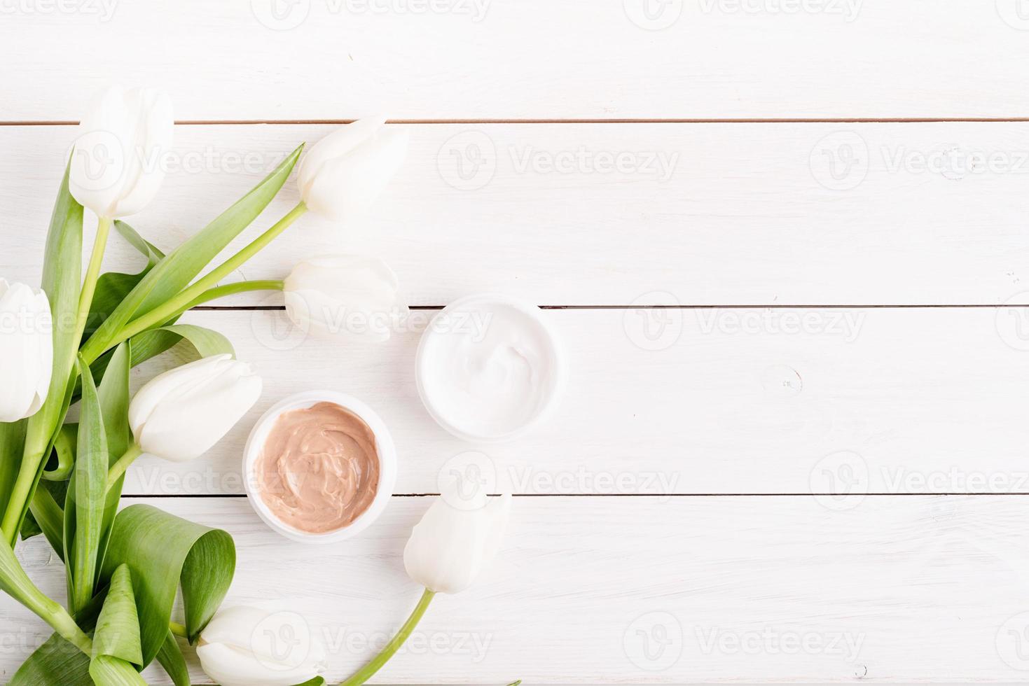 Cosmetic creams with white tulips top view flat lay photo