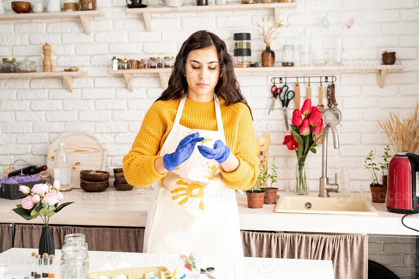 young woman coloring easter eggs in the kitchen photo