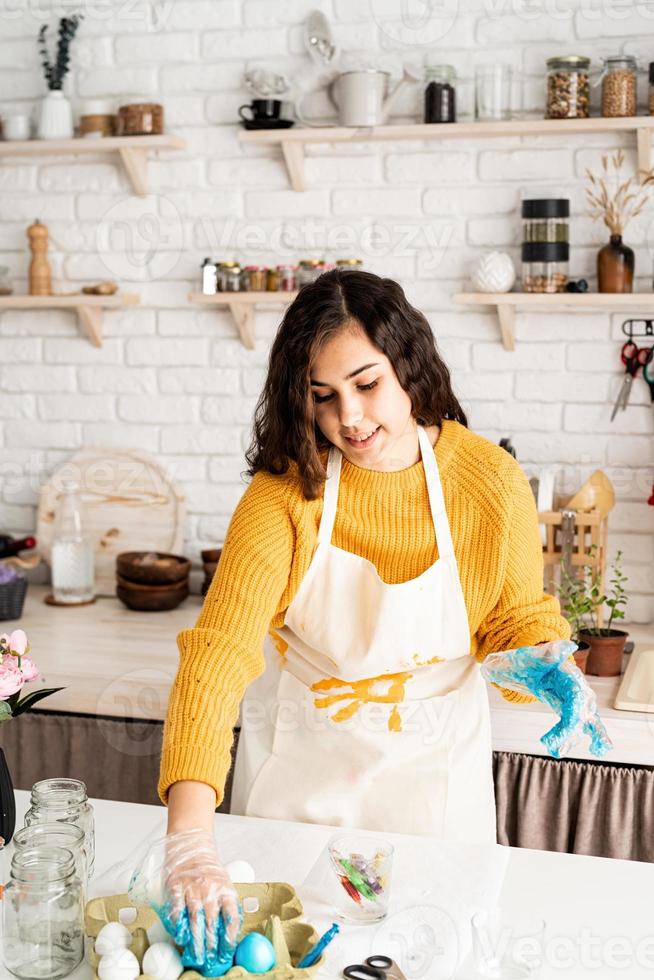 Mujer coloreando huevos de pascua azul en la cocina foto