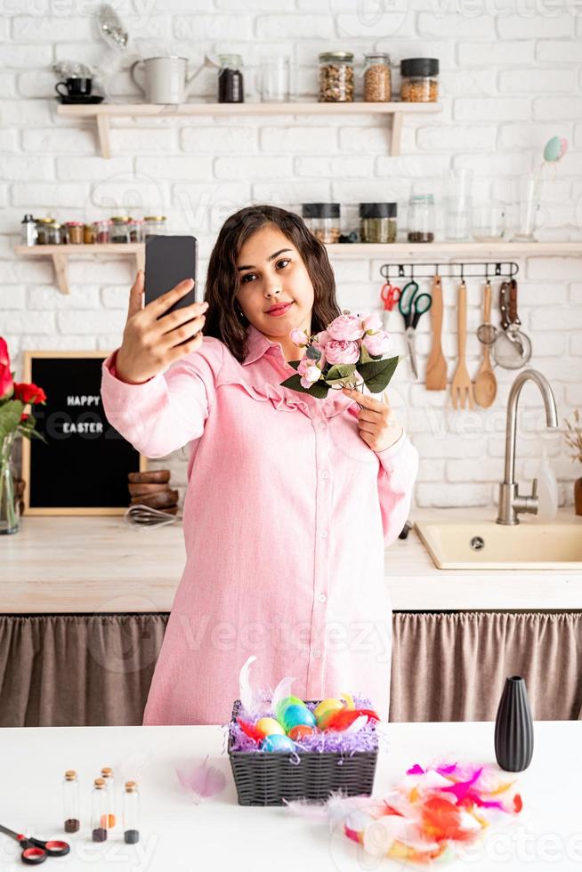 Beautiful woman taking selfie using mobile phone in the kitchen photo