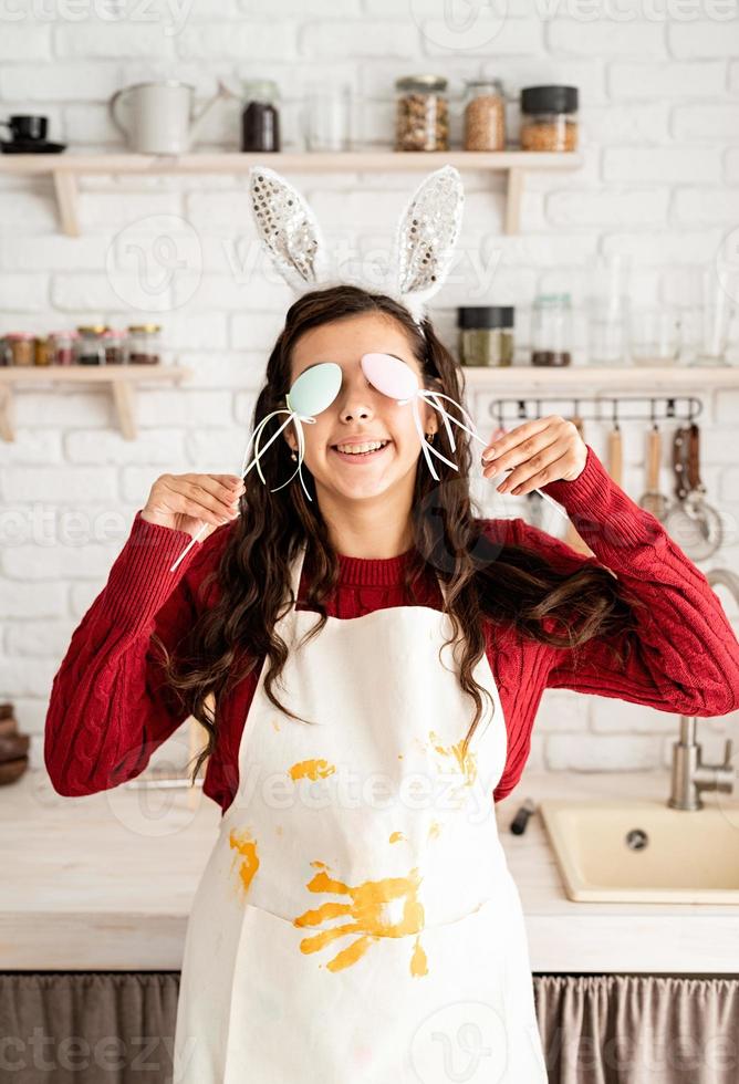 Mujer de orejas de conejo cubriéndose los ojos con decoraciones de huevos de pascua foto