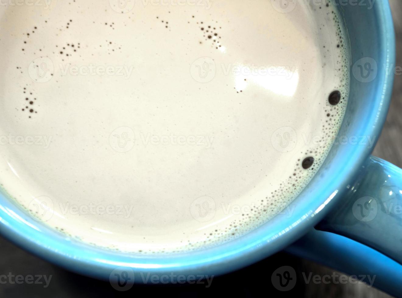 Milk in a blue cup on the wooden and top glass table photo