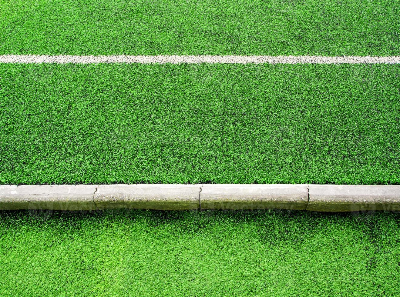 Texture of plastic artificial grass and concrete border of school yard photo