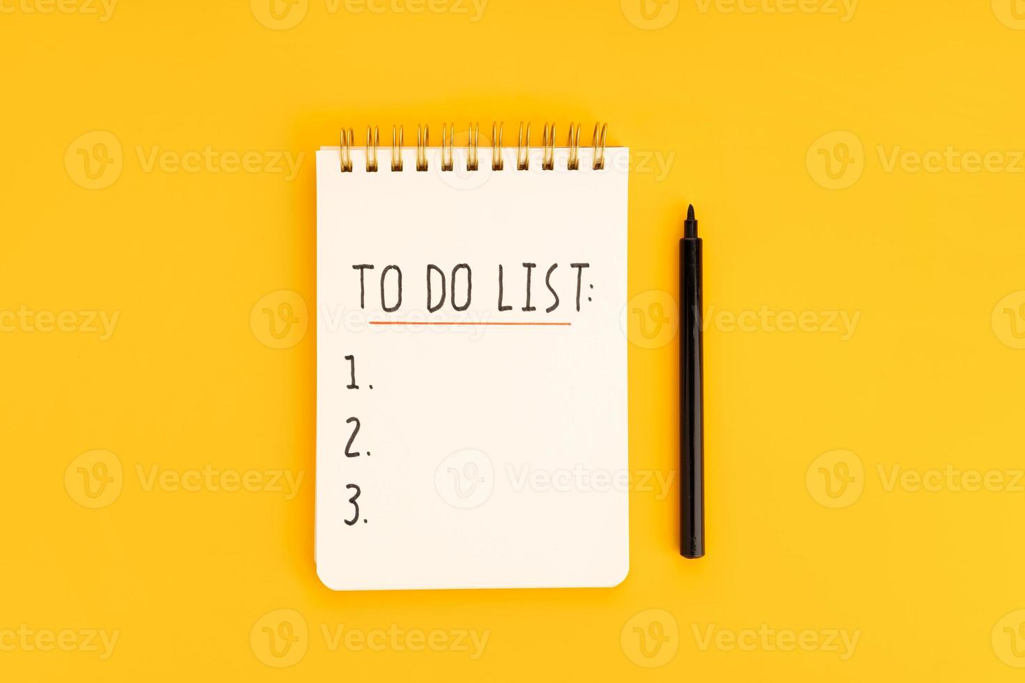 To do list in spiral notepad isolated on yellow background. Top view photo