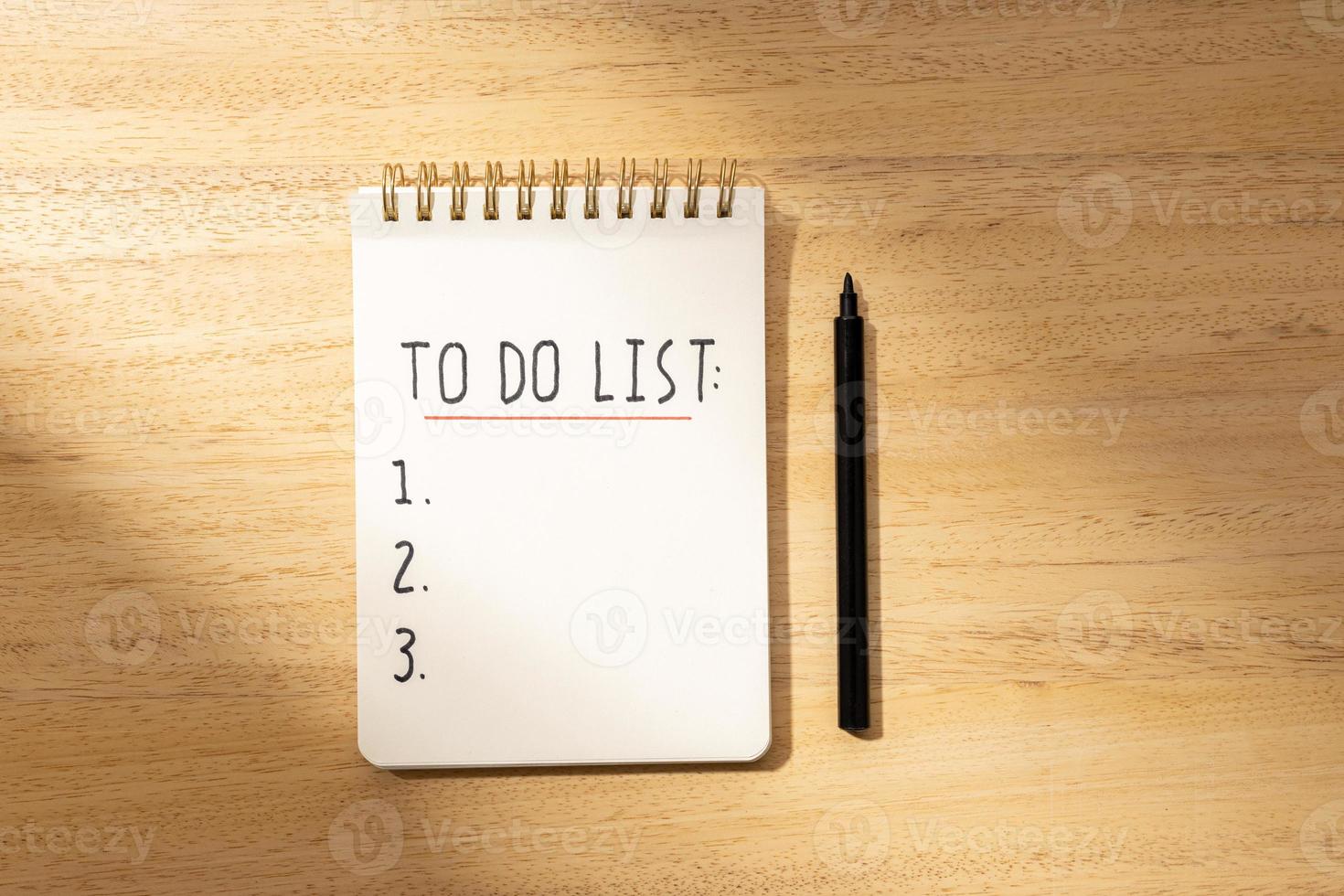 To do list in spiral notepad isolated on wooden desk. Flat lay photo