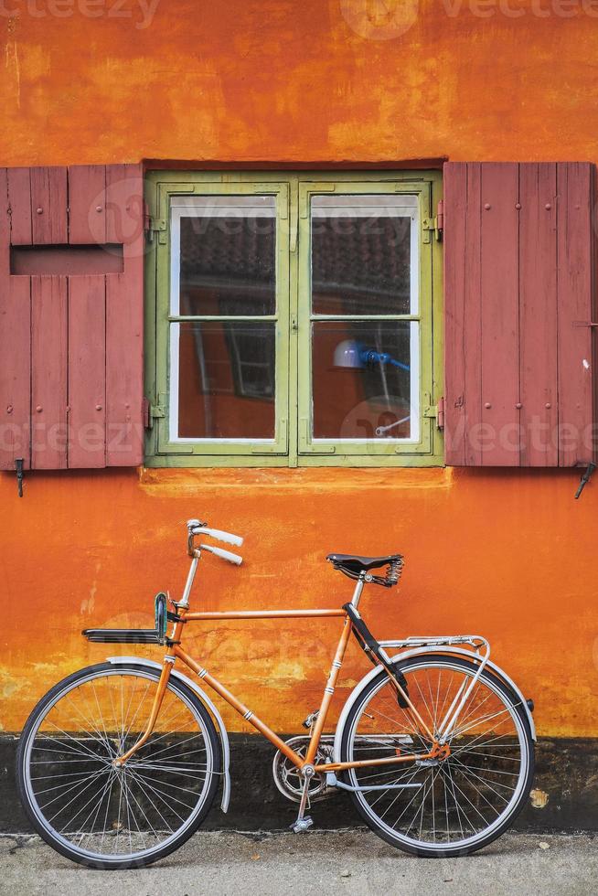 Ventanas con pared naranja y bicicleta vintage. foto