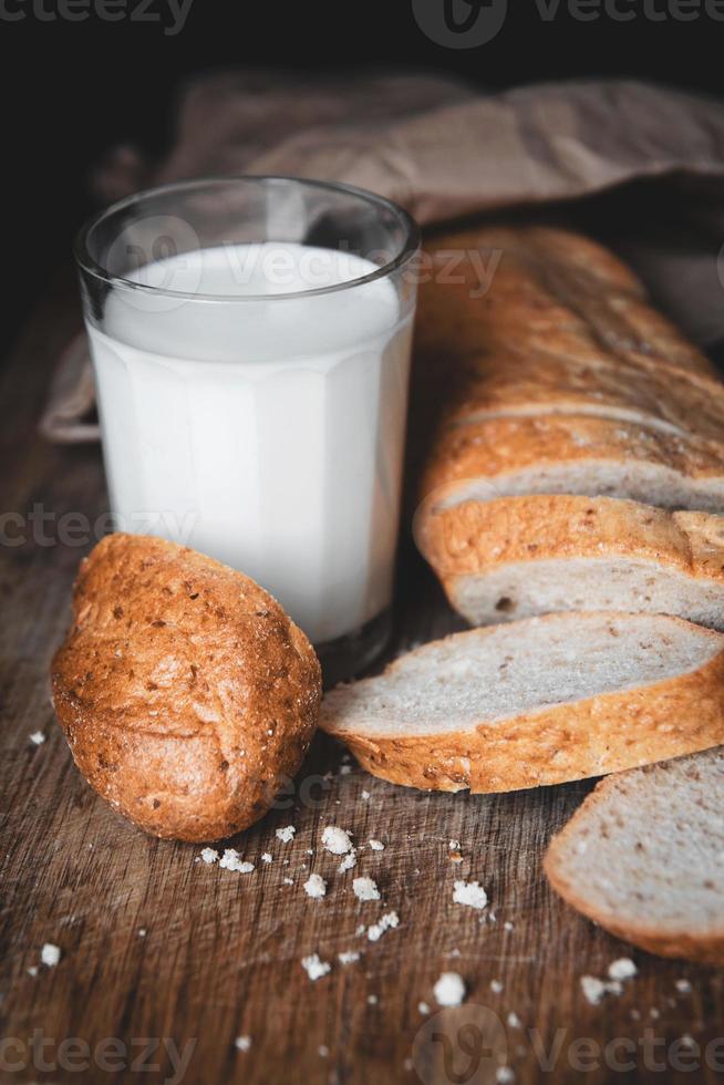 pan con trozos cortados se encuentran sobre una tabla de madera y un vaso de leche fresca foto