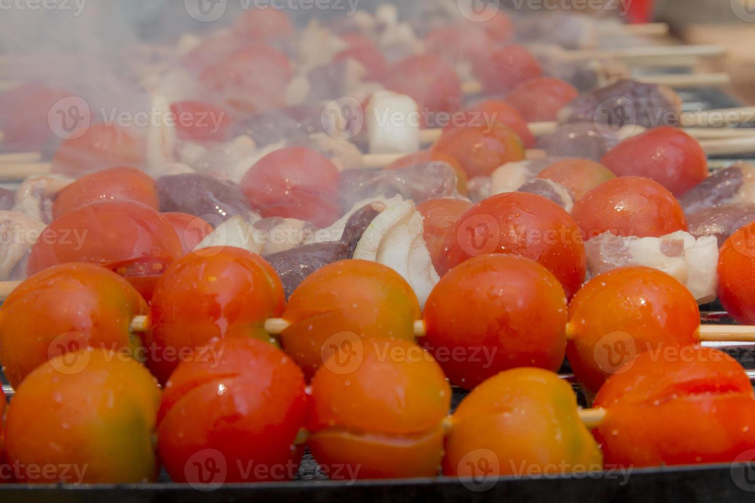 Corazones de pollo con tomate y cebolla cocinar a la parrilla caliente foto