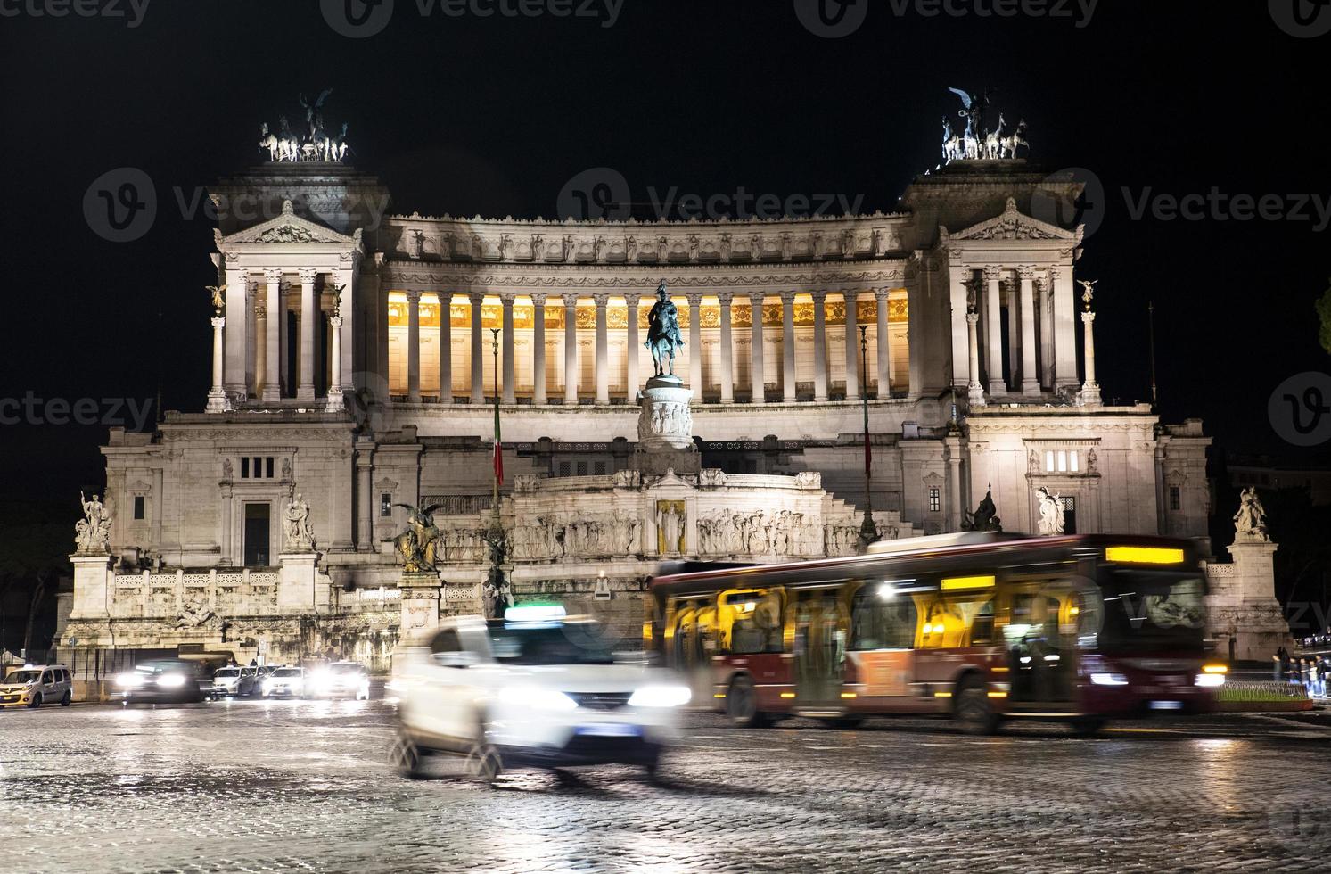 Plaza de Venecia con vehículos en movimiento en Roma, Italia por la noche foto