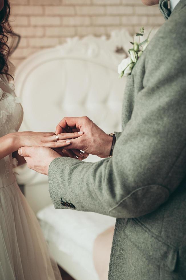 A closeup view of bride and groom exchanging rings, vertical image photo