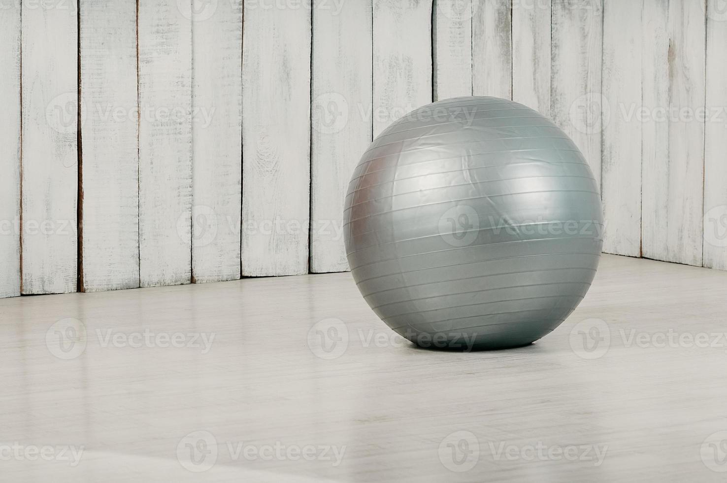 Grey fitball in a gym, light floor and background photo