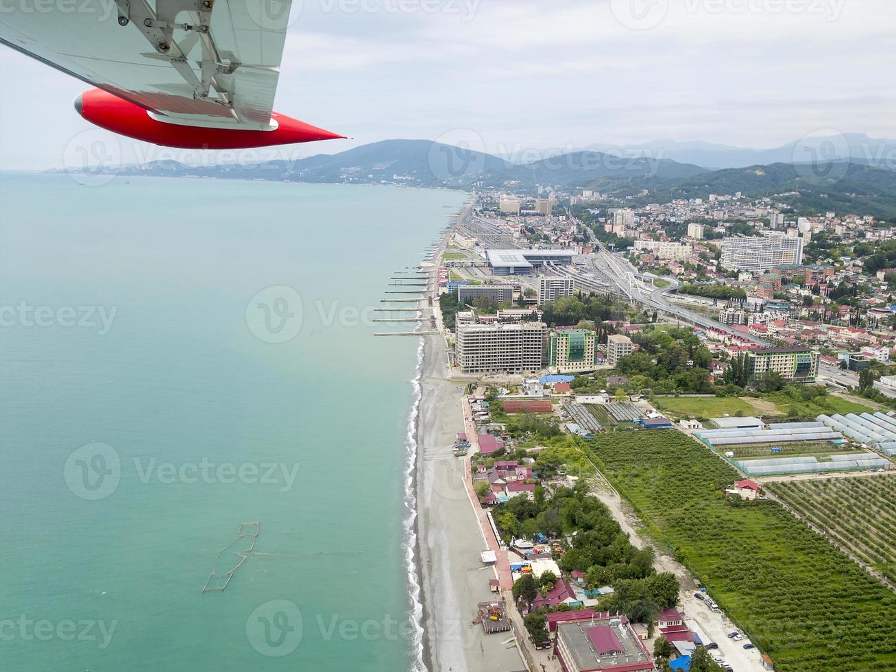 The wing of a plane flying by the sea, panorama of the coast photo