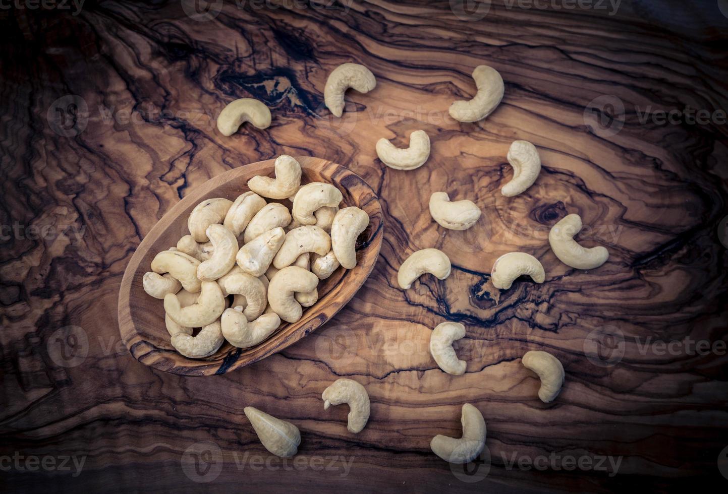 un montón de anacardos en madera de olivo foto