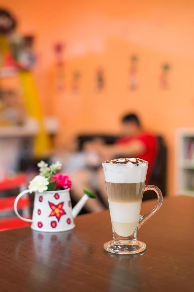 Cup of coffee with flower lobe pattern in reveal cup on wooden table. photo