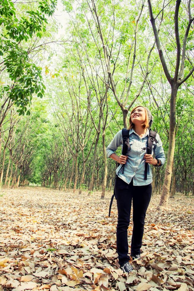 hermosa mujer joven con mochila caminando en el bosque. foto