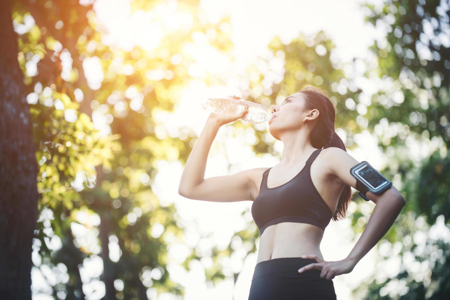 fitness mujer atleta toma un descanso, agua potable, día caluroso. foto