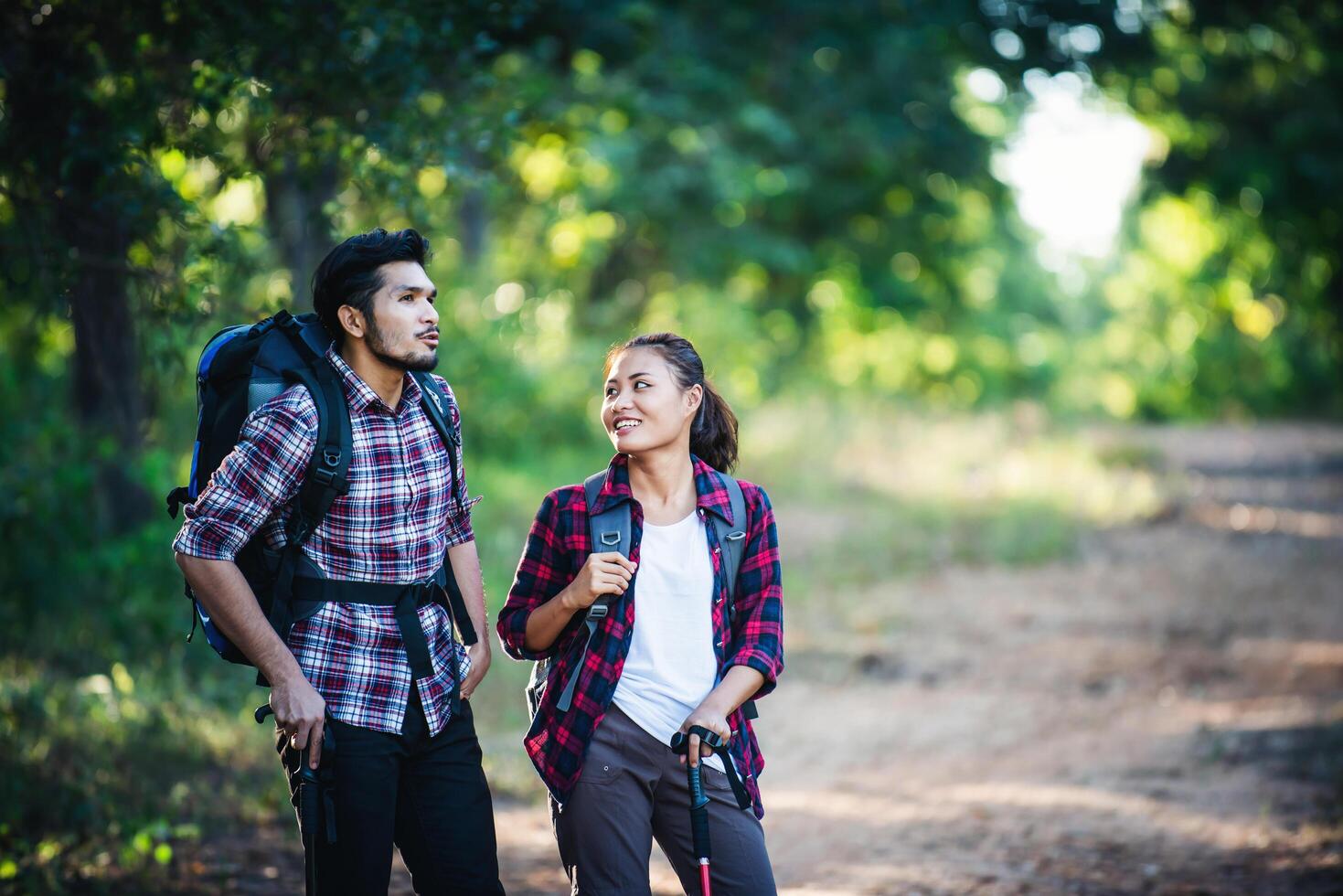 pareja joven caminando con mochilas en el bosque. caminatas de aventura. foto