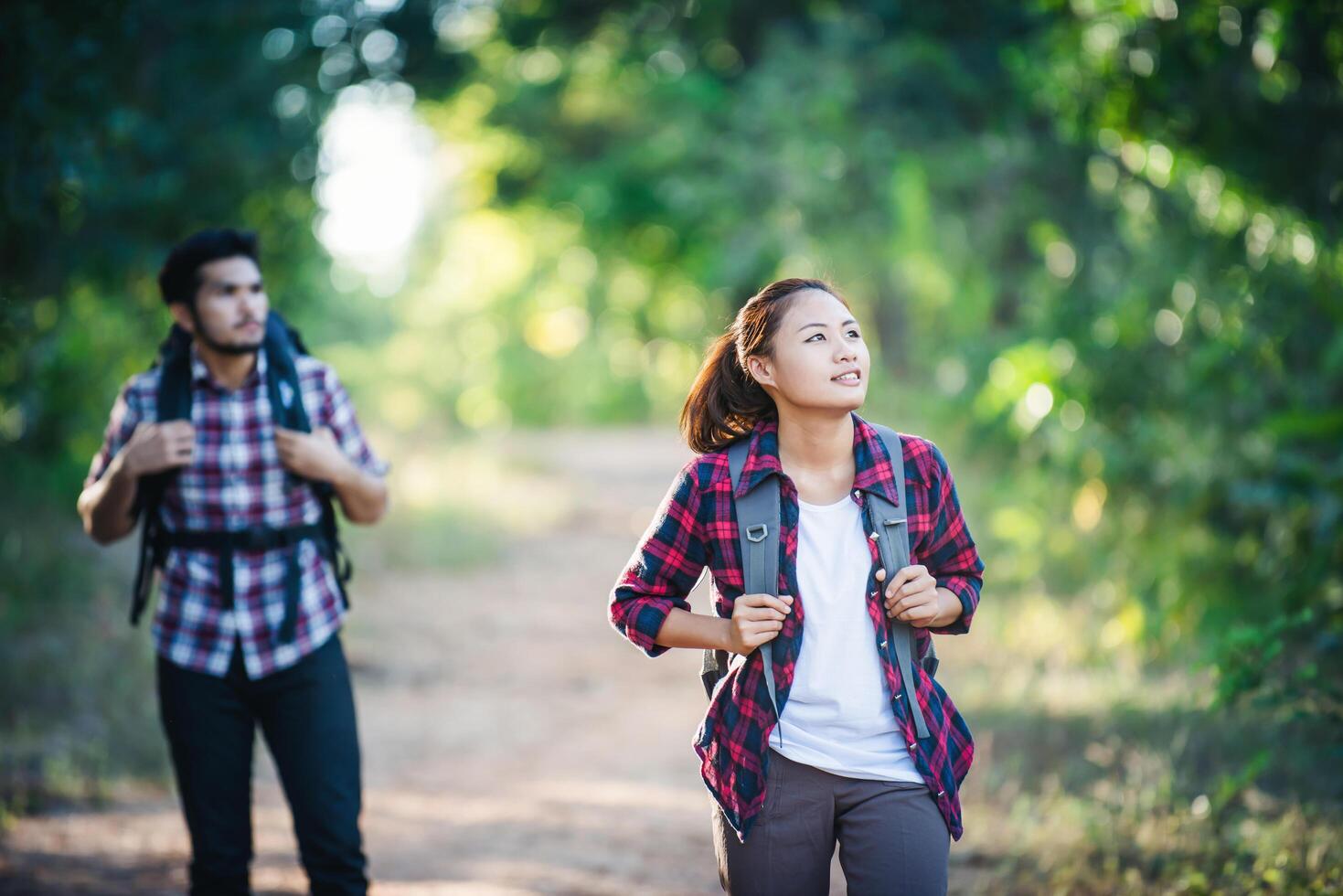 Young couple walking with backpacks in forest. Adventure hikes. photo