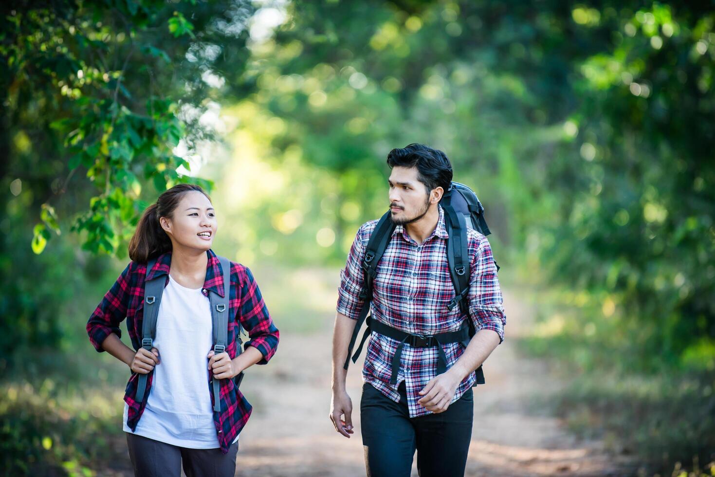 pareja joven caminando con mochilas en el bosque. caminatas de aventura. foto