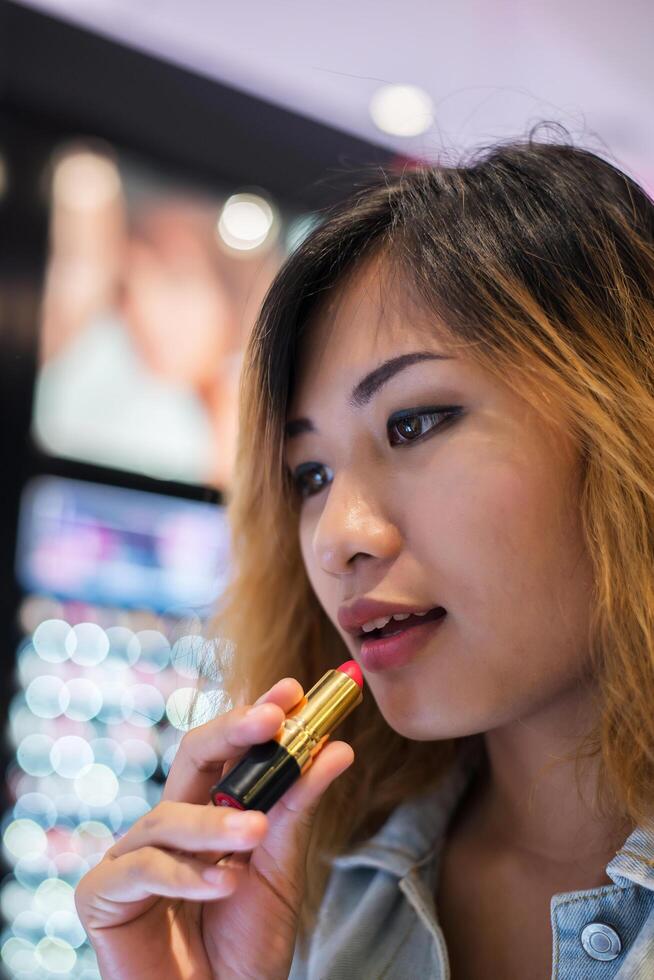 Beautiful young woman select color lipstick to buying at shopping mall photo