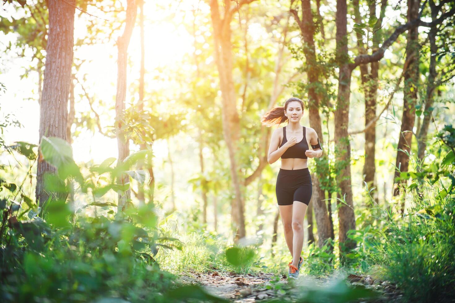 Young woman jogging on rural road in green forest nature. photo