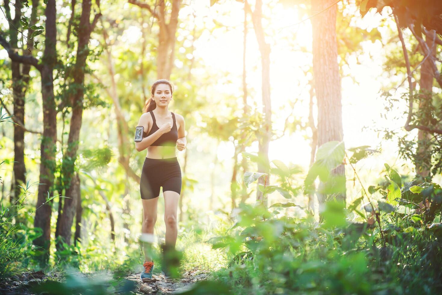 Young woman jogging on rural road in green forest nature. photo