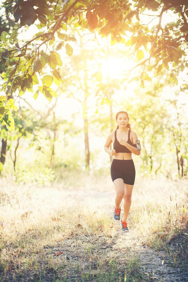 mujer joven para correr en un camino rural en la naturaleza del bosque. foto