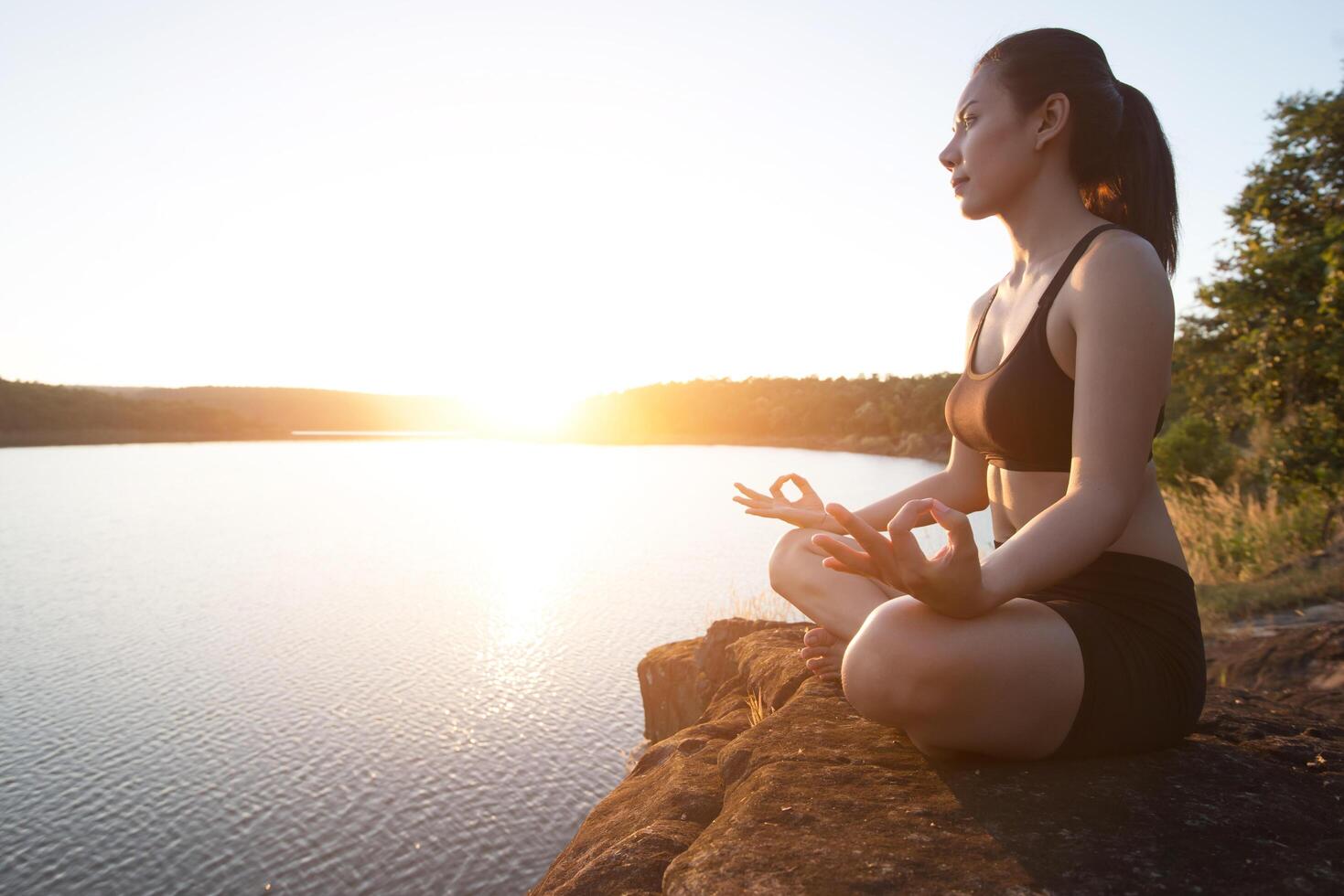 joven sana está practicando yoga en el lago de la montaña durante la puesta de sol. foto