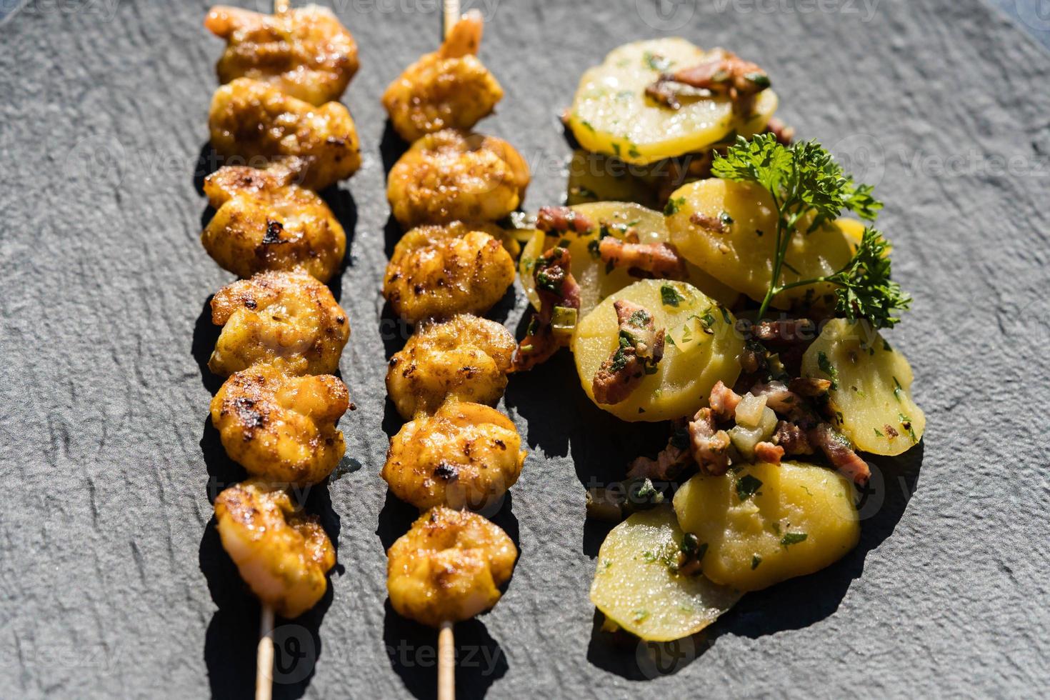 Langostinos tigre blancos a la plancha con ensalada de bacon y patatas foto