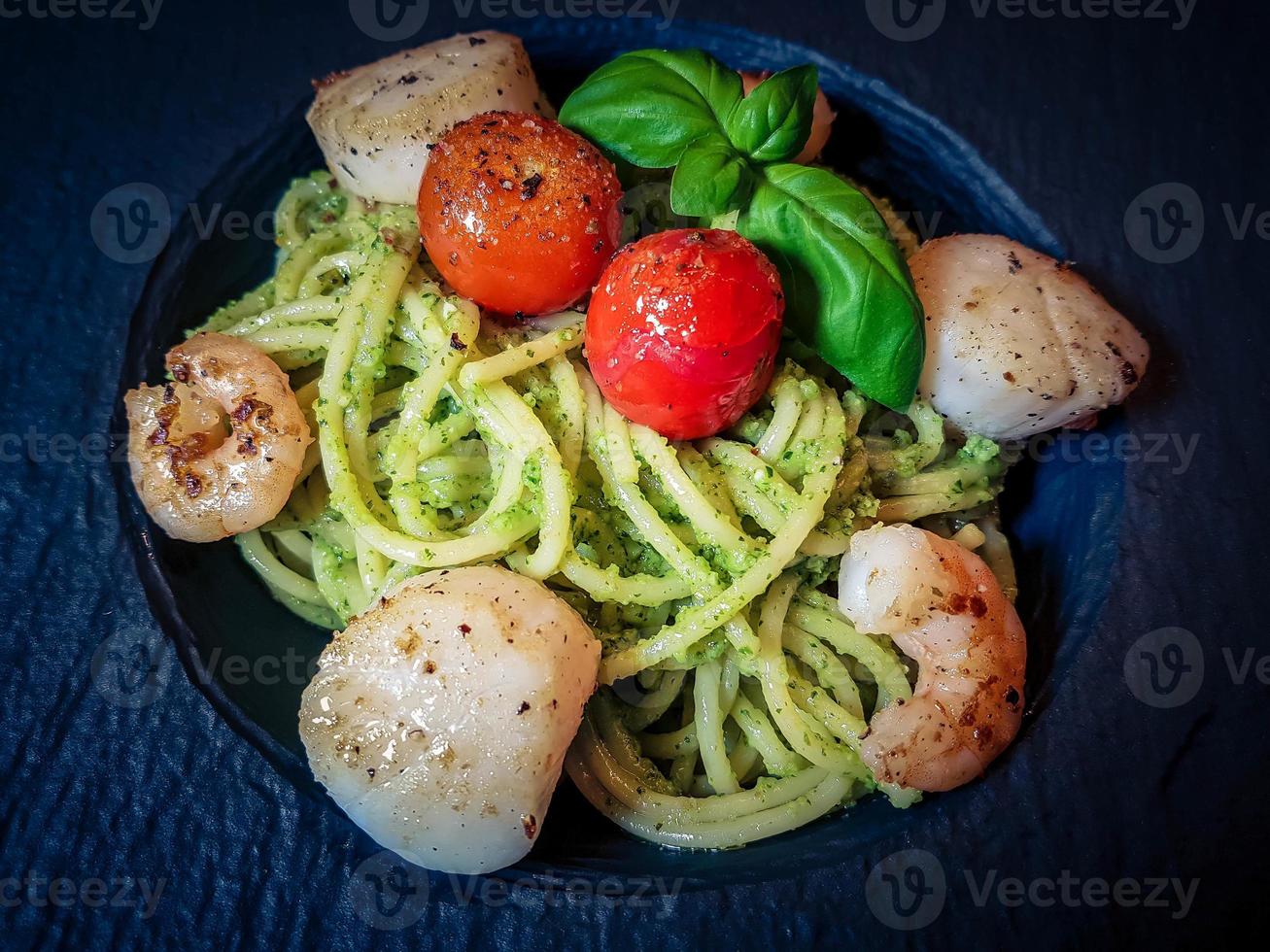 Fried saltwater seashells on spaghetti with green pesto photo