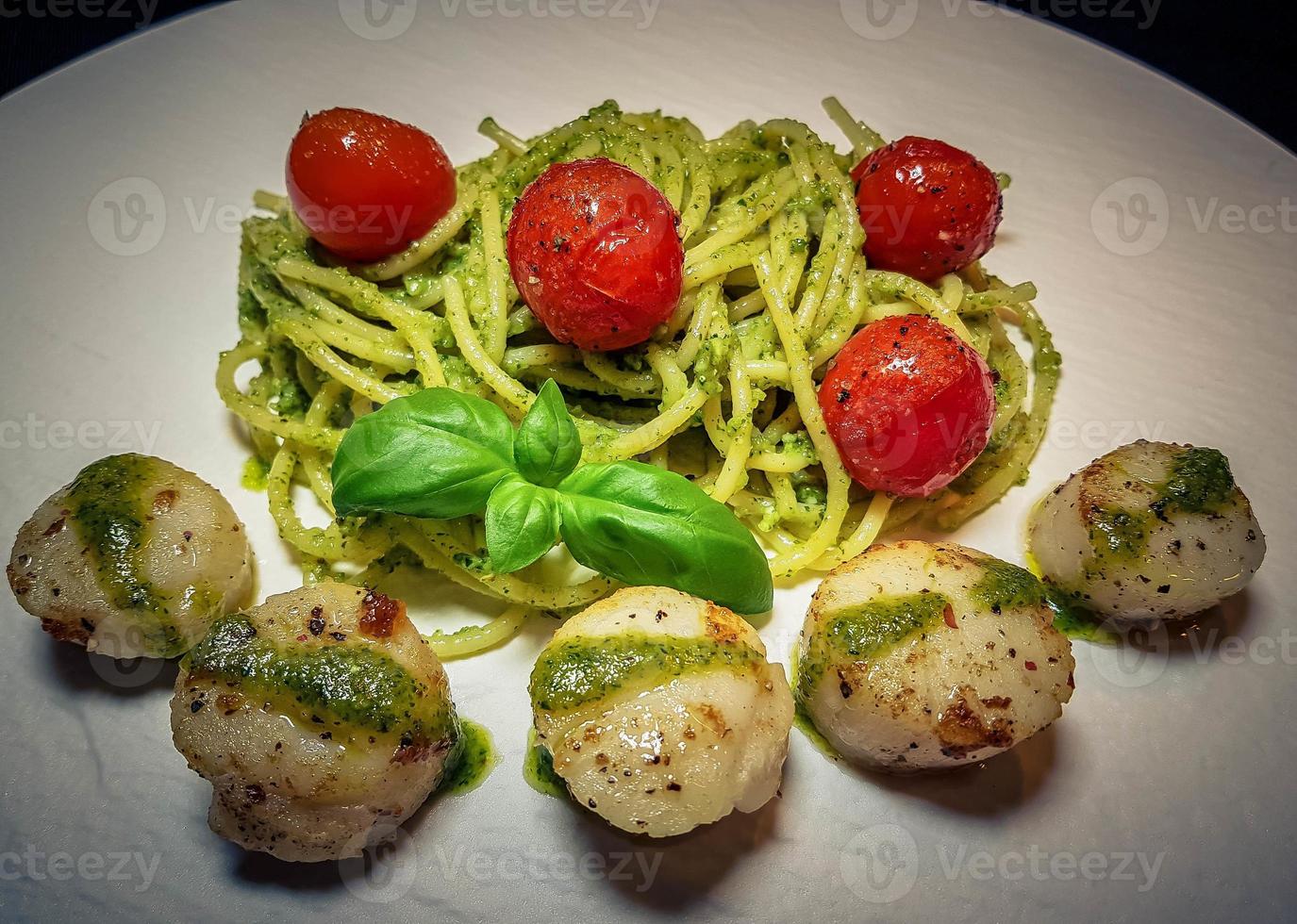 Conchas de agua salada fritas sobre espaguetis con pesto verde foto