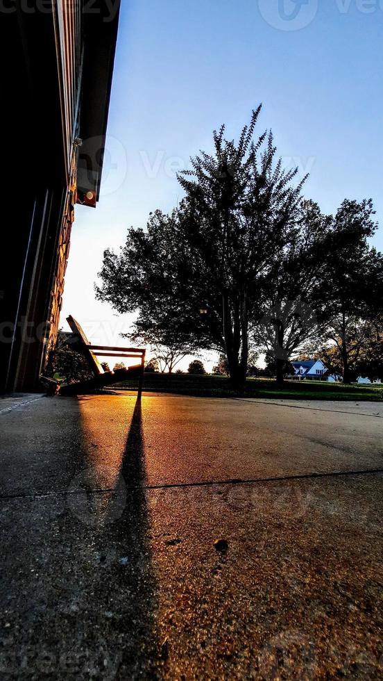 hermosa puesta de sol con sombras de silla adirondack cerca de la casa foto