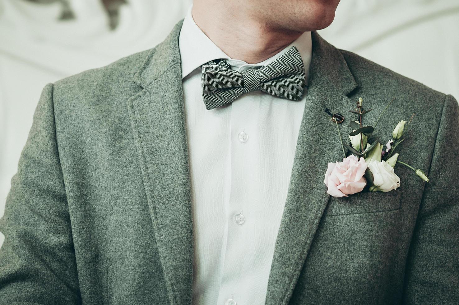 un novio con traje gris y camisa blanca preparándose para el evento foto