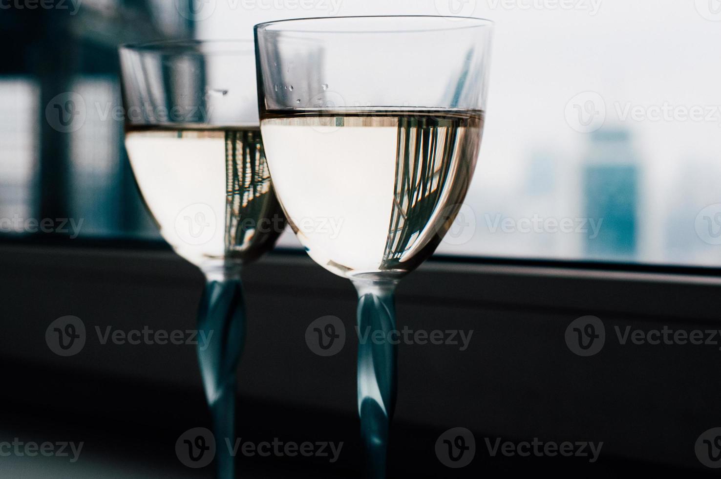 Dos copas de vino blanco en el alféizar de la ventana, hermosos reflejos foto