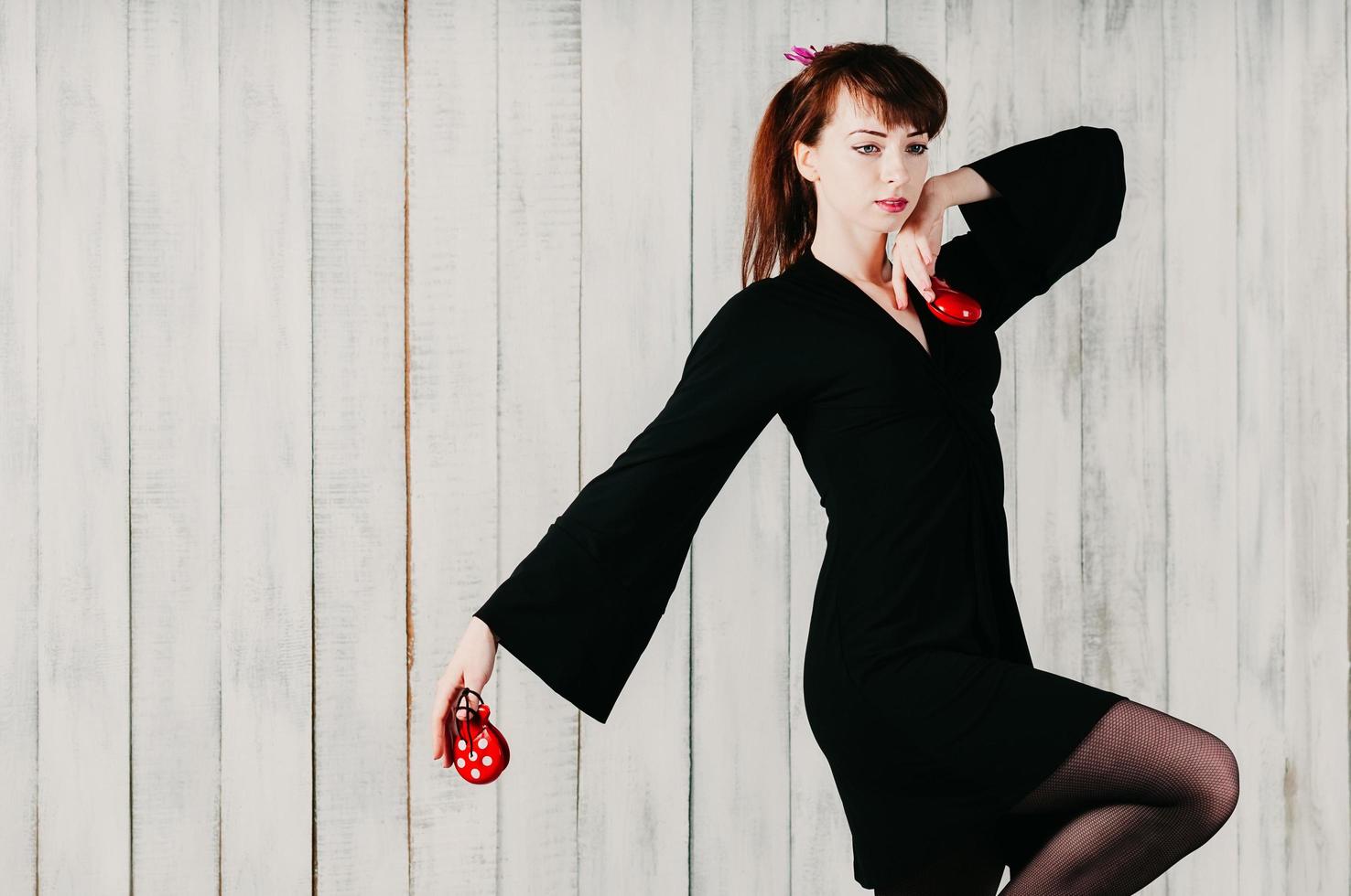 A young dancing girl in black dress, with castanets, light background photo